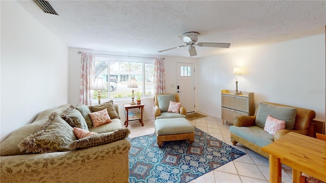 living room featuring light tile patterned floors, a textured ceiling, ceiling fan, and visible vents