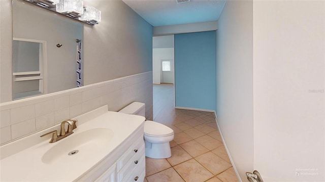 bathroom with tile walls, visible vents, toilet, vanity, and tile patterned flooring
