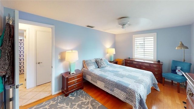 bedroom with baseboards, visible vents, and wood finished floors