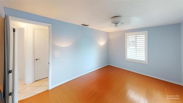 unfurnished room with wood finished floors, baseboards, and visible vents
