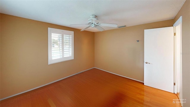 empty room featuring baseboards, visible vents, a ceiling fan, and wood finished floors