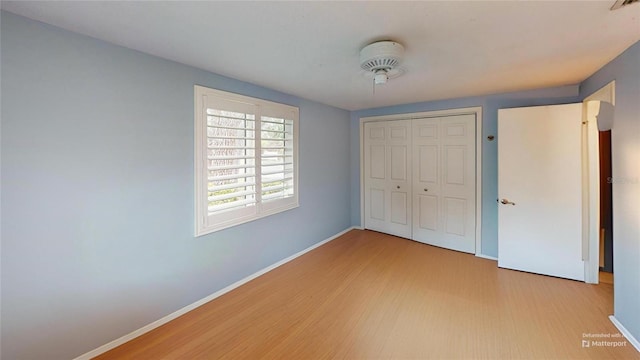 unfurnished bedroom with baseboards, a closet, and light wood-type flooring