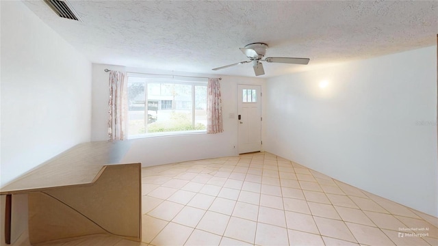 empty room with a textured ceiling, ceiling fan, and visible vents