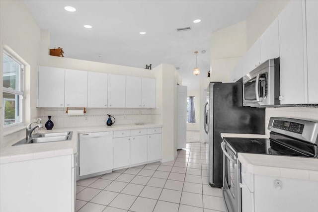 kitchen featuring a sink, light countertops, white cabinetry, stainless steel appliances, and decorative backsplash