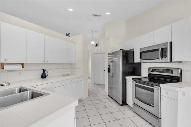 kitchen with white cabinetry, visible vents, a sink, stainless steel appliances, and decorative backsplash