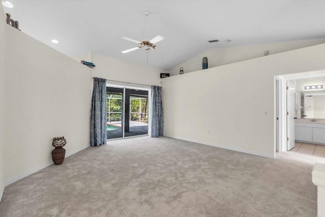 spare room with light carpet, ceiling fan, baseboards, and vaulted ceiling