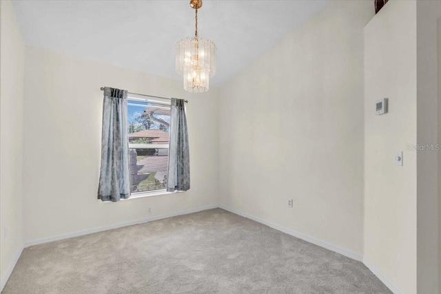 unfurnished room featuring an inviting chandelier, baseboards, and carpet