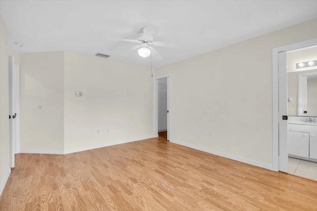 spare room with baseboards, light wood-style flooring, visible vents, ceiling fan, and a sink