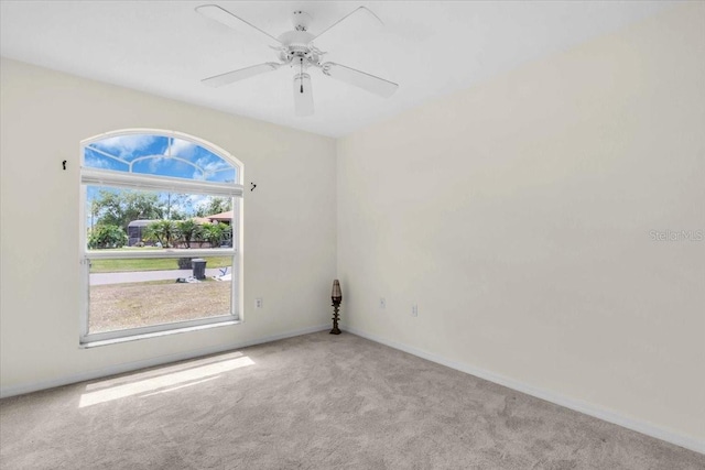 carpeted empty room featuring ceiling fan and baseboards