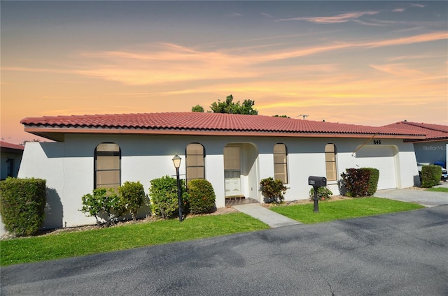 mediterranean / spanish-style house featuring stucco siding, an attached garage, and a tiled roof