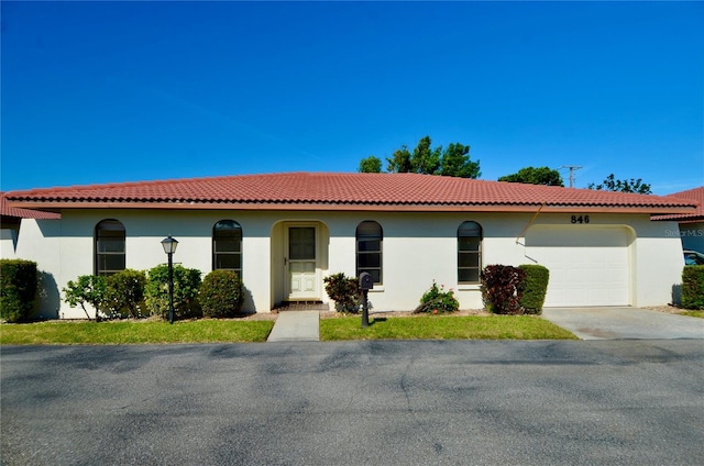mediterranean / spanish-style home with a tile roof, concrete driveway, stucco siding, and a garage