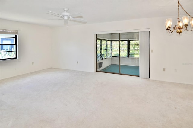 spare room featuring ceiling fan with notable chandelier, plenty of natural light, and carpet