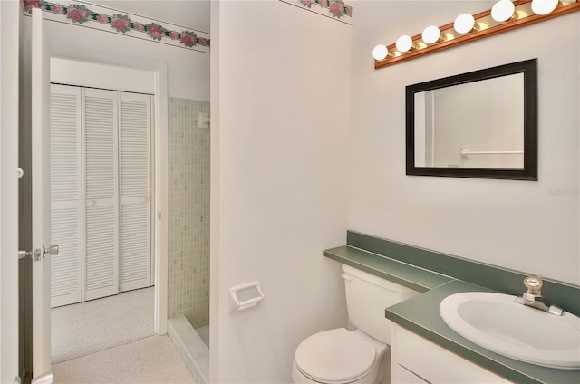 bathroom featuring a closet, toilet, vanity, and a shower stall