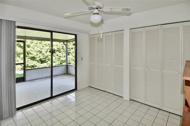 unfurnished bedroom featuring access to outside, multiple closets, ceiling fan, and light tile patterned floors
