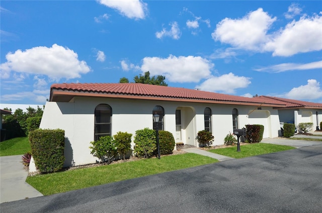 mediterranean / spanish-style house featuring driveway, stucco siding, an attached garage, and a tiled roof