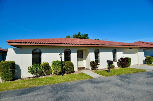 mediterranean / spanish home featuring a tiled roof, a garage, and stucco siding