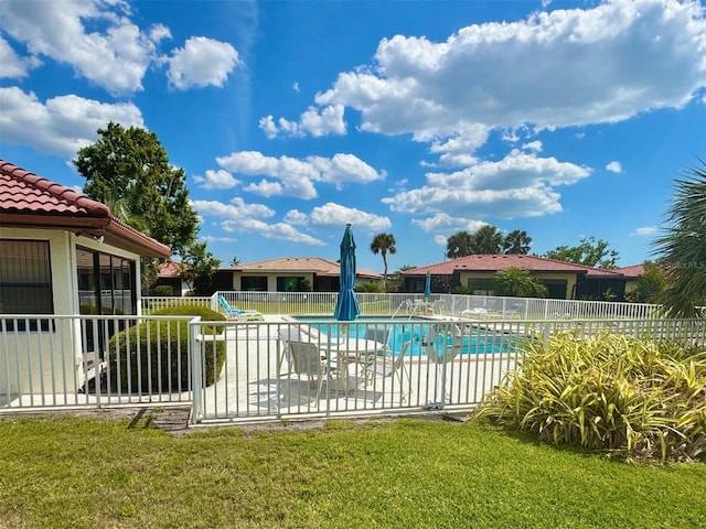 community pool with a lawn, fence, and a patio