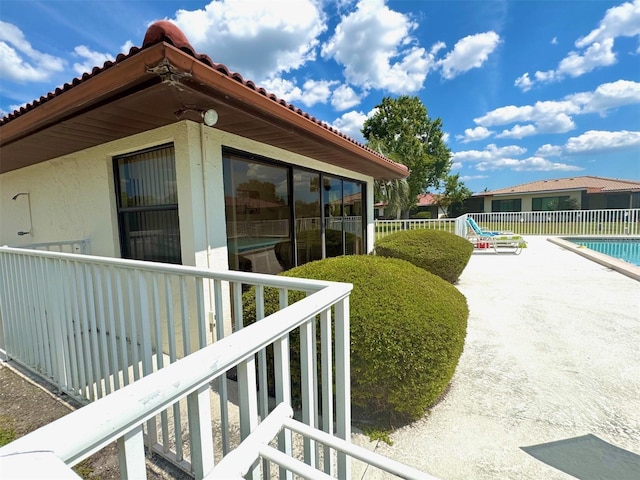 view of home's exterior featuring fence, stucco siding, a patio, and a fenced in pool