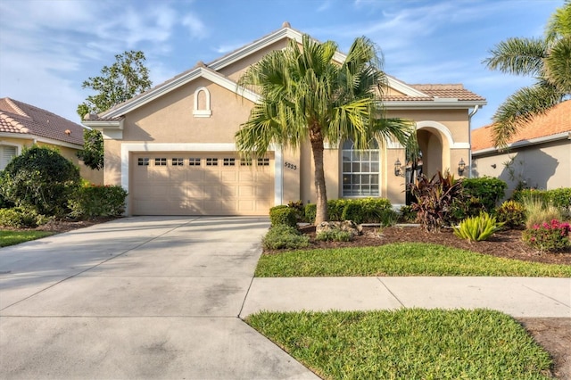 view of front of house with driveway, stucco siding, a tile roof, and a garage