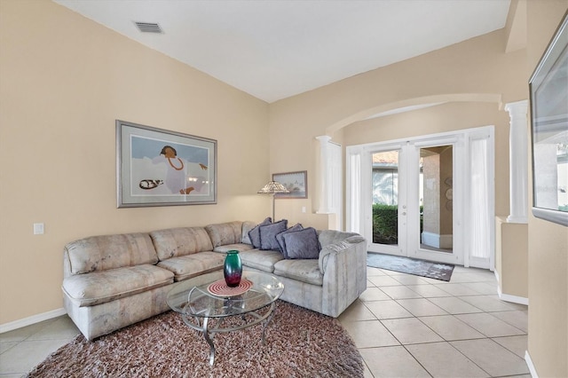 living area with arched walkways, visible vents, decorative columns, and light tile patterned floors