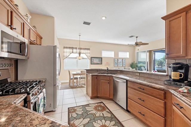 kitchen with a sink, backsplash, brown cabinets, and appliances with stainless steel finishes