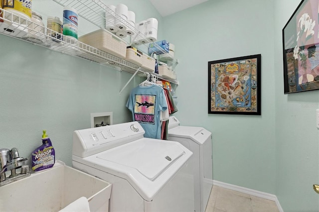 laundry area featuring baseboards, light tile patterned flooring, a sink, washing machine and dryer, and laundry area