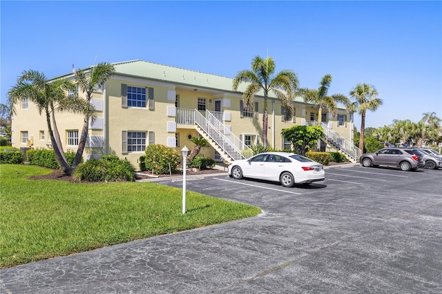 view of property featuring uncovered parking and stairway