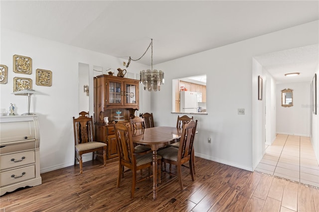 dining area with baseboards, a chandelier, and wood finished floors