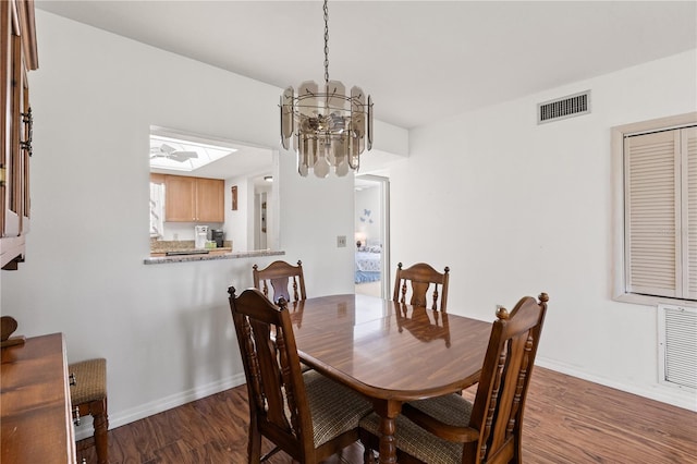 dining room with baseboards, visible vents, wood finished floors, and a chandelier