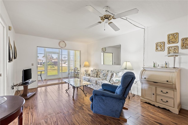 living area featuring a ceiling fan, baseboards, and wood finished floors