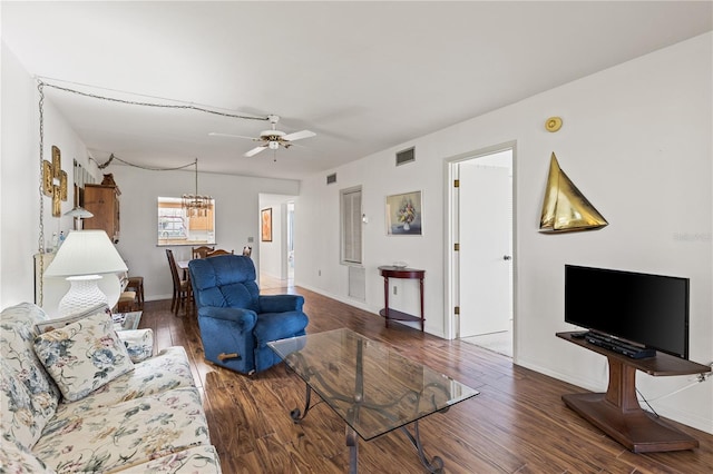 living area featuring wood finished floors, ceiling fan with notable chandelier, baseboards, and visible vents