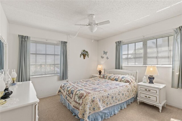 bedroom featuring ceiling fan, baseboards, light colored carpet, and a textured ceiling