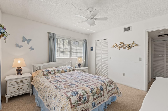 carpeted bedroom with a ceiling fan, a textured ceiling, a closet, and visible vents