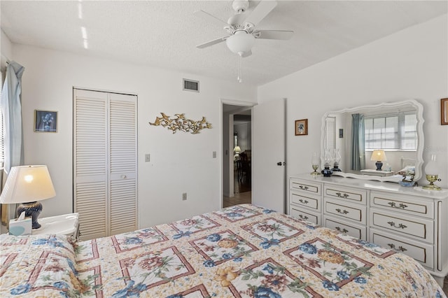 bedroom featuring visible vents, a closet, ceiling fan, and a textured ceiling