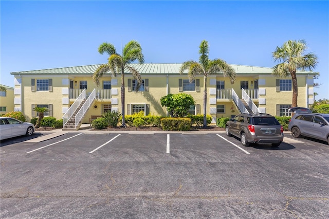 view of property featuring uncovered parking and stairway