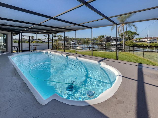 outdoor pool featuring a water view, glass enclosure, a yard, and a patio area