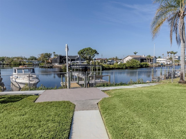 view of dock featuring a gate, a water view, fence, and a lawn