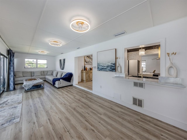 living area with wood finished floors, baseboards, and visible vents