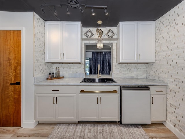 kitchen with white cabinets, light wood-style flooring, a sink, and tasteful backsplash