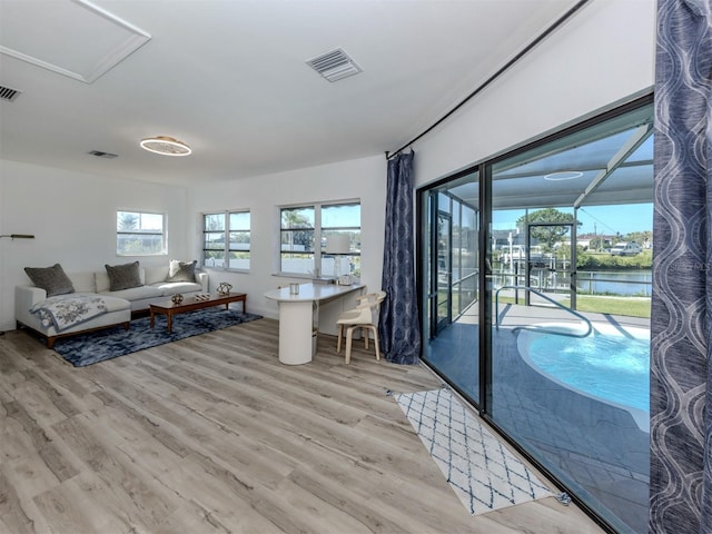 living area with a water view, visible vents, and light wood-type flooring