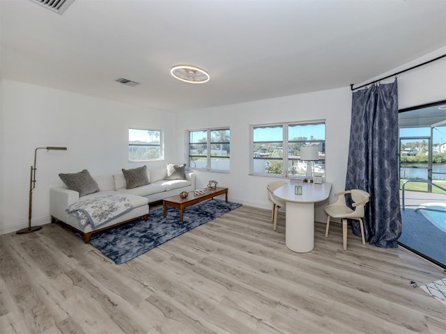 living area featuring baseboards, visible vents, and light wood finished floors