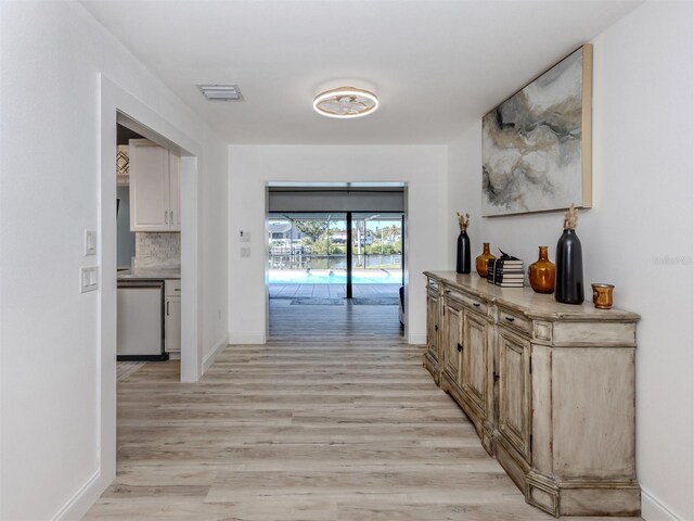 corridor with baseboards, visible vents, and light wood-style flooring