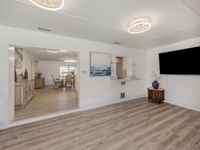 unfurnished living room featuring baseboards, visible vents, and light wood-type flooring
