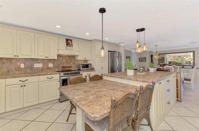 403 Picasso Dr, Nokomis, FL 34275 - kitchen with backsplash, cream cabinets, light tile patterned flooring, a kitchen island, and appliances with stainless steel finishes