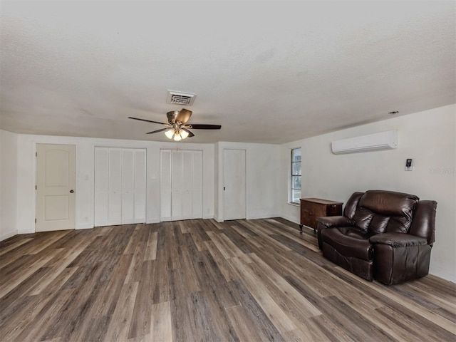 200 Sierra St S, Nokomis, FL 34275 - living room featuring a ceiling fan, a textured ceiling, a wall mounted air conditioner, and wood finished floors
