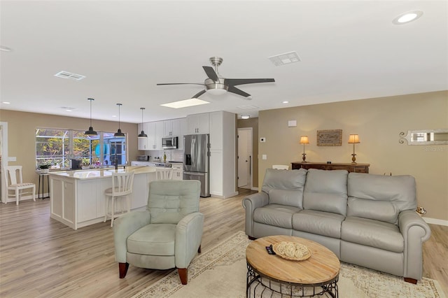 living area featuring baseboards, visible vents, and light wood finished floors