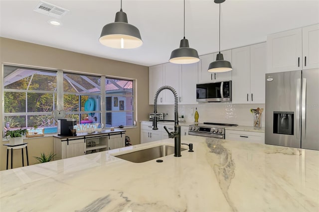 kitchen featuring visible vents, appliances with stainless steel finishes, tasteful backsplash, a sink, and light stone counters