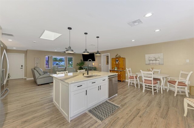 kitchen with a sink, dishwasher, light wood finished floors, and visible vents