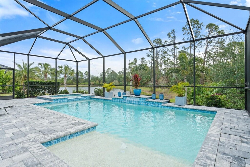 view of swimming pool with glass enclosure, a pool with connected hot tub, and a patio area