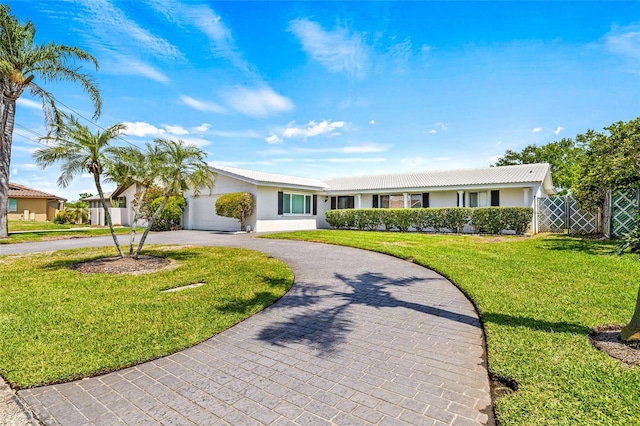 ranch-style house with a front yard, fence, stucco siding, and curved driveway